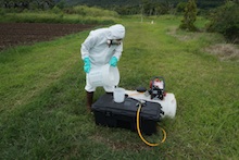 Worker measuring water to calibrate hand-held sprayer system